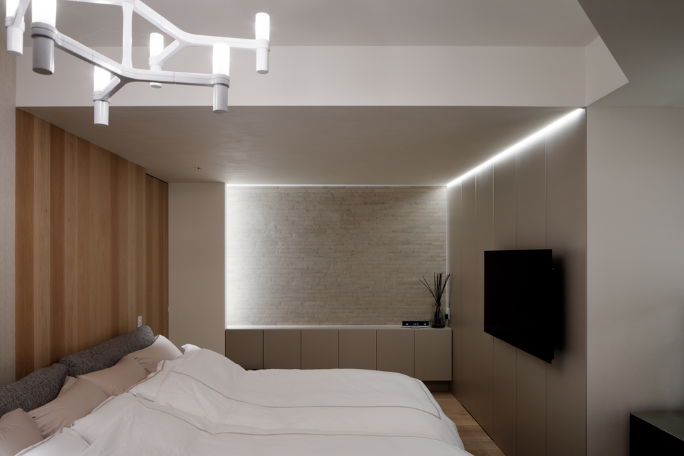 間接照明がアクセントになっている主寝室。実はTV横は収納のため、収納用照明としての機能性も。ベッド横の木の扉はファミリークローゼットへもアクセス出来るようになっています。
